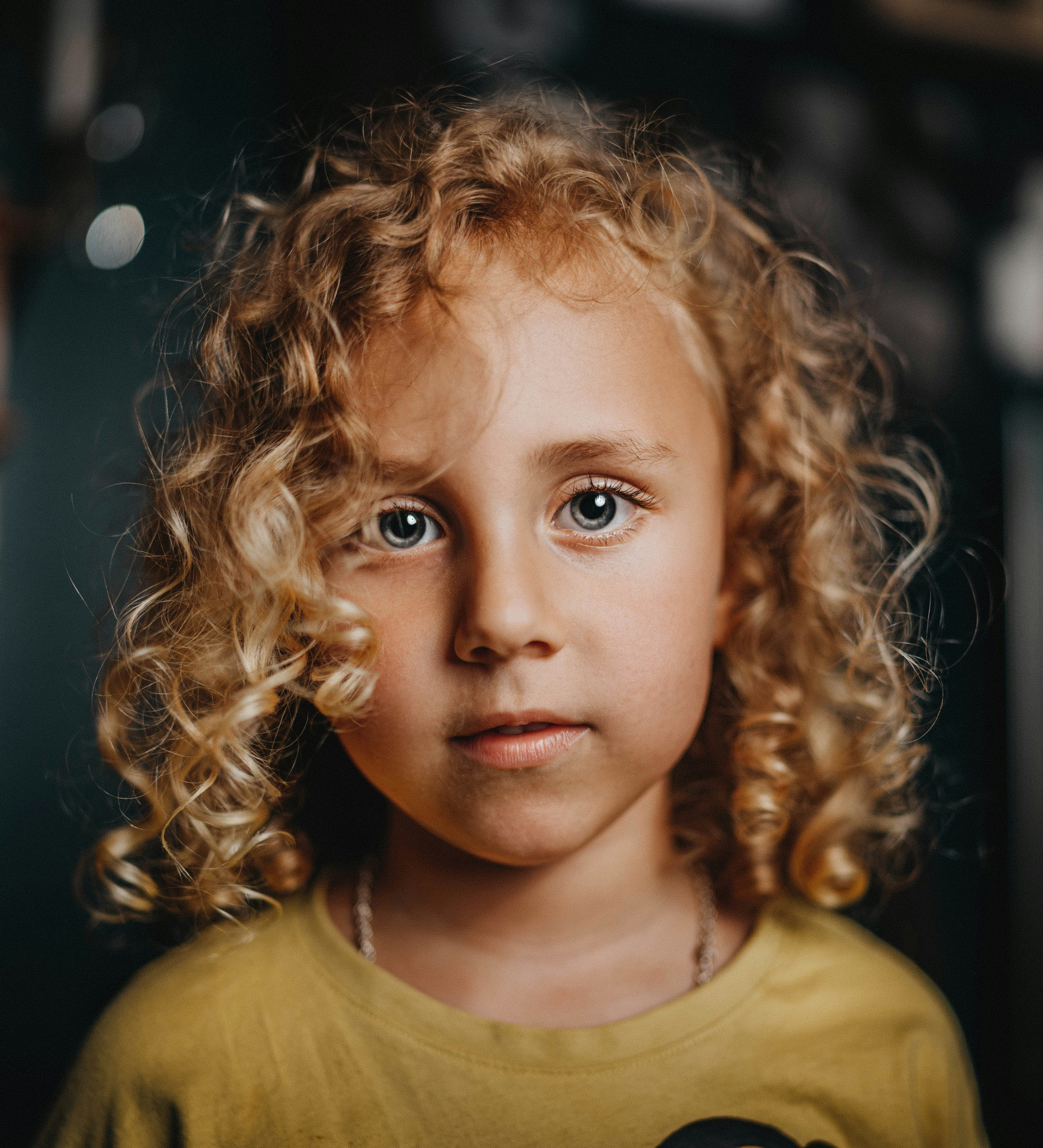 A young child with curly hair smiling warmly at the camera